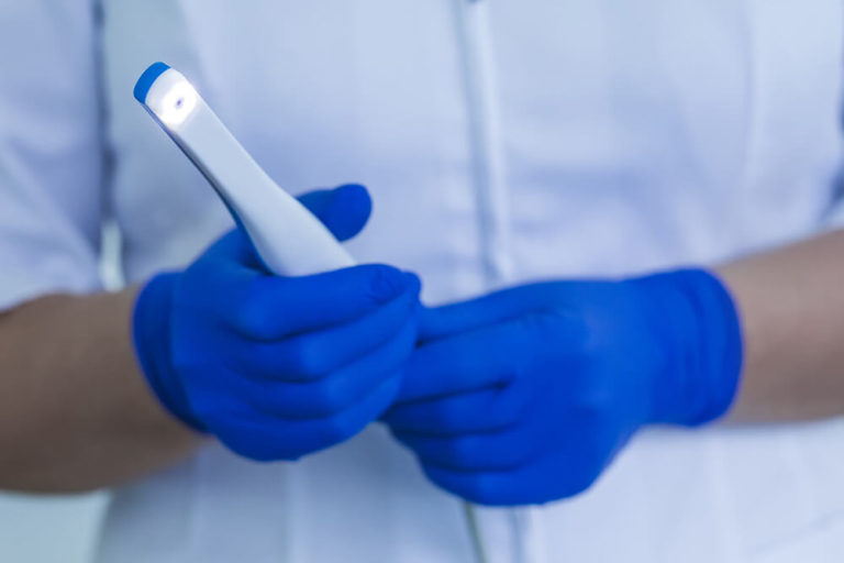 A dental assistant holding an intraoral camera