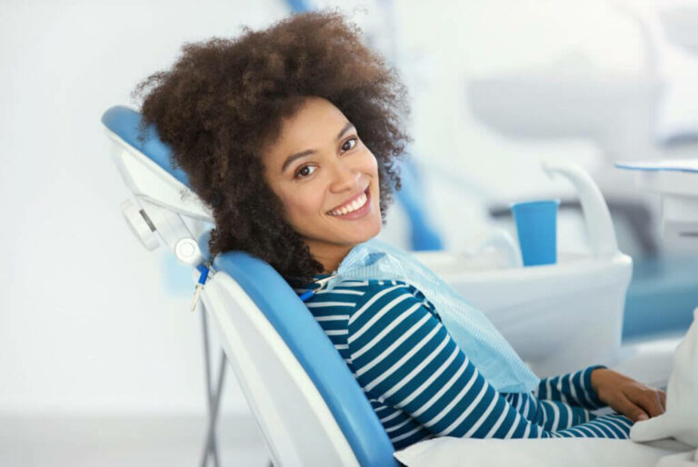 woman sitting in dental chair, smiling at the camera
