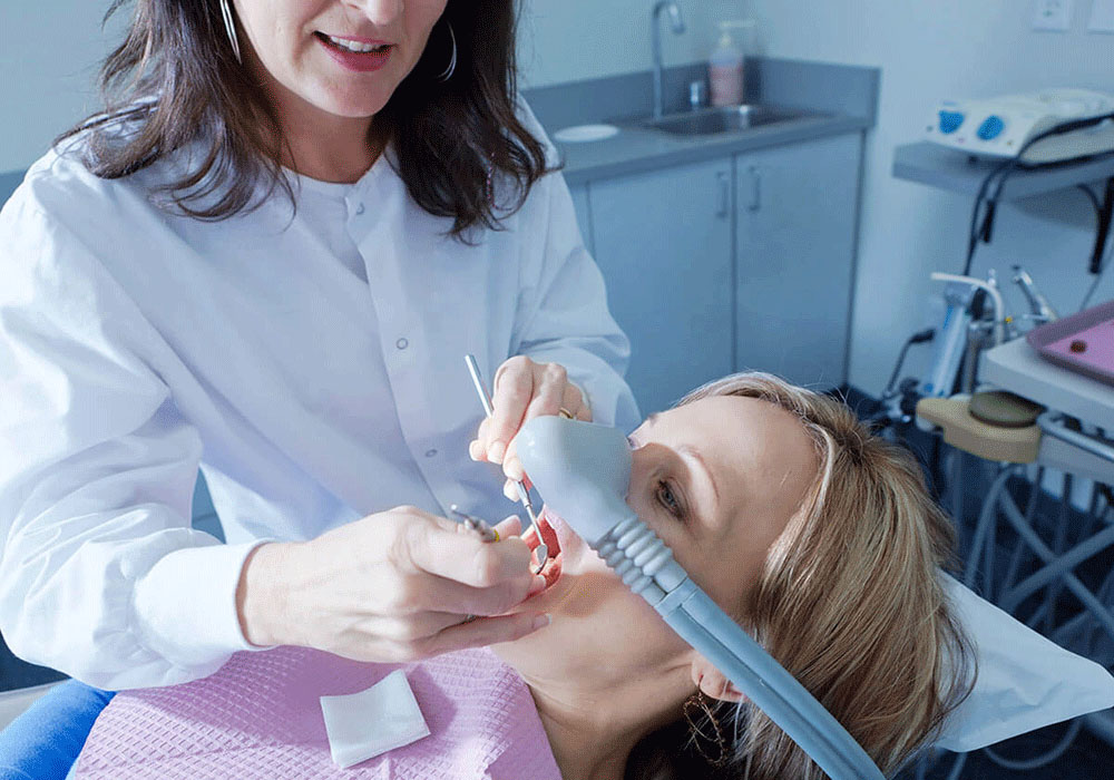 patient being sedated while the doctor checks her teeth