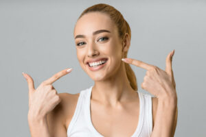 smiling female pointing with both hands, at her white teeth