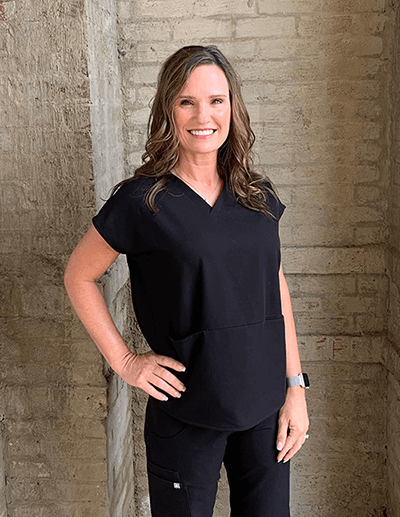 Team member Vanessa of Hall Cosmetic & Family Dentistry, wearing a black scrub against a wall.