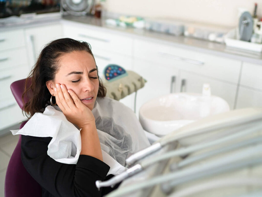 a women in an operating chair having some tooth discomfort